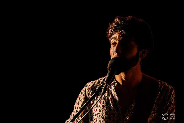 Ravi Brasileiro canta ao microfone em luz baixa